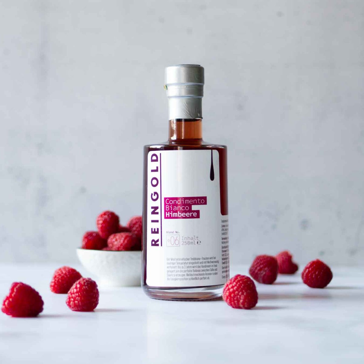 Reingold Himbeerbalsam-Flasche mit frischen Himbeeren auf Tisch.