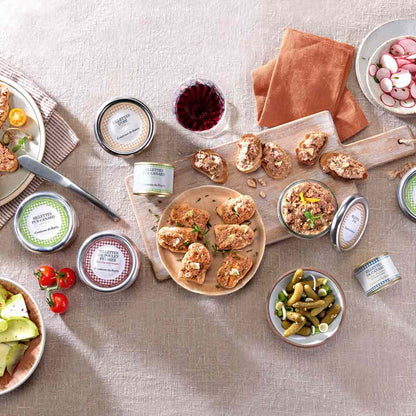 Verschiedene Rillettes, Brot, Wein, Gemüse auf einem Tisch.