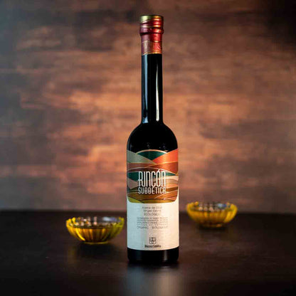 Flasche Rincon Subbetica Olivenöl auf Tisch mit Schalen.