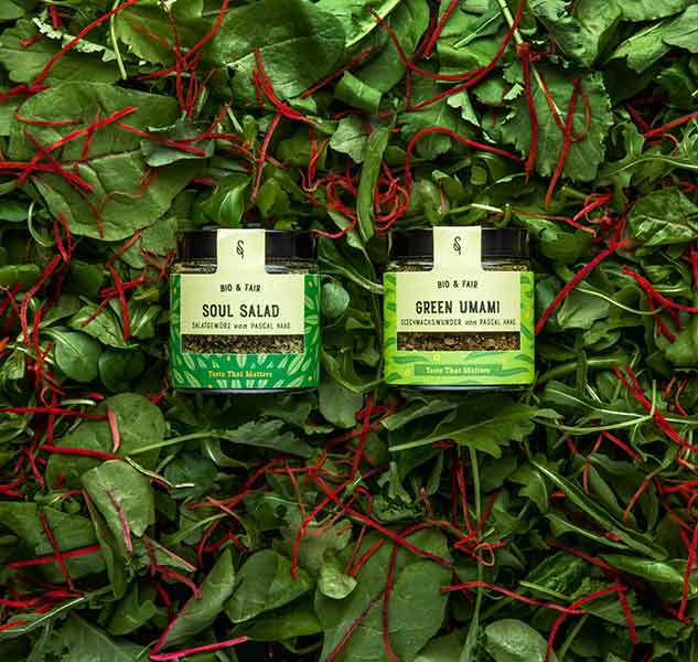 Zwei Gewürzgläser auf Salatbett mit roten Streifen.