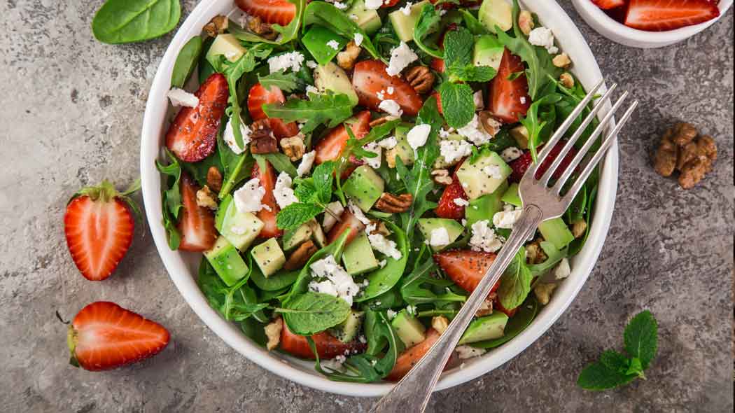 Salat mit Erdbeeren, Avocado, Feta, Nüssen und Balsamico.