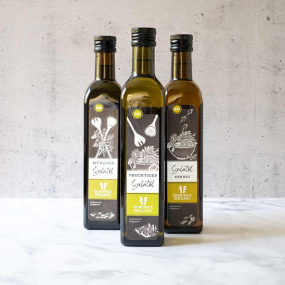 Drei Flaschen Olivenöl von Ölmühle Solling auf Tisch.