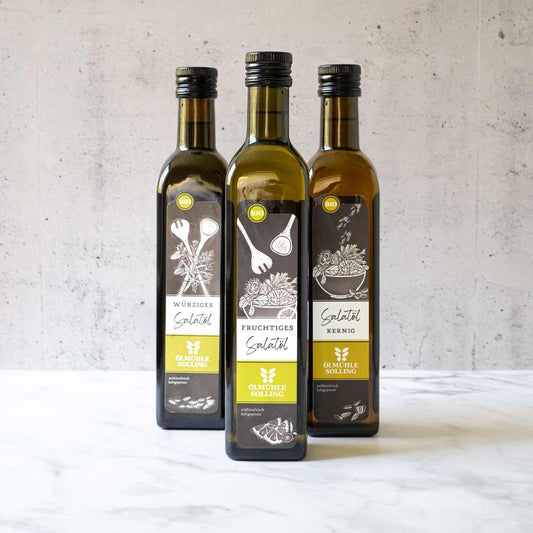 Drei Flaschen Olivenöl von Ölmühle Solling auf Tisch.