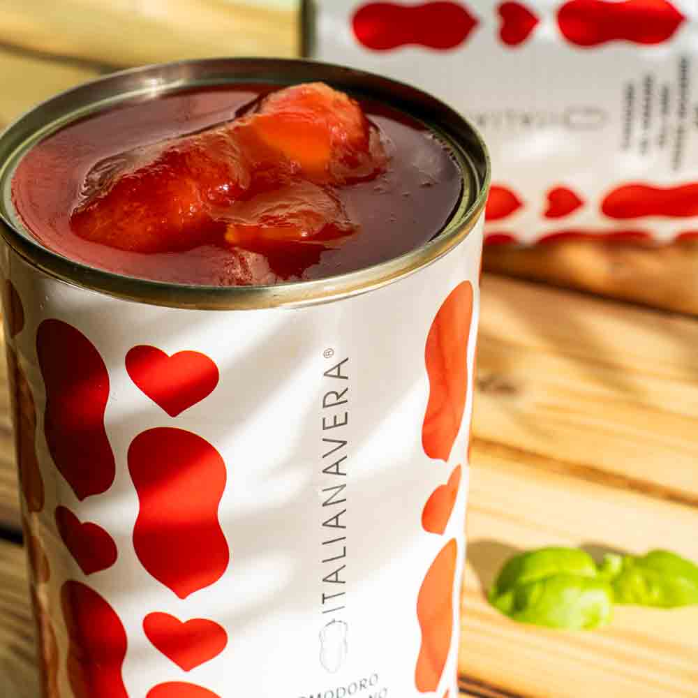 Italienische Tomatendose Italianavera auf Holztisch mit Basilikum.