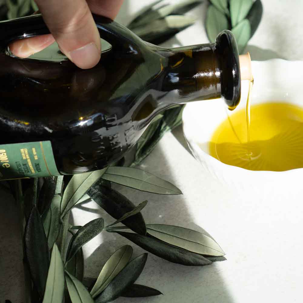 Olivenöl wird in eine Schale gegossen, Olivenzweige.