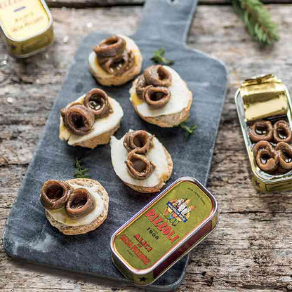 Sardellen auf Brot mit Rizzoli-Dosen auf Holzbrett.
