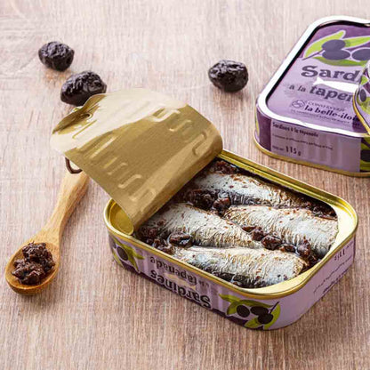 Sardinen mit Oliven-Tapenade in geöffneter Dose auf Tisch.