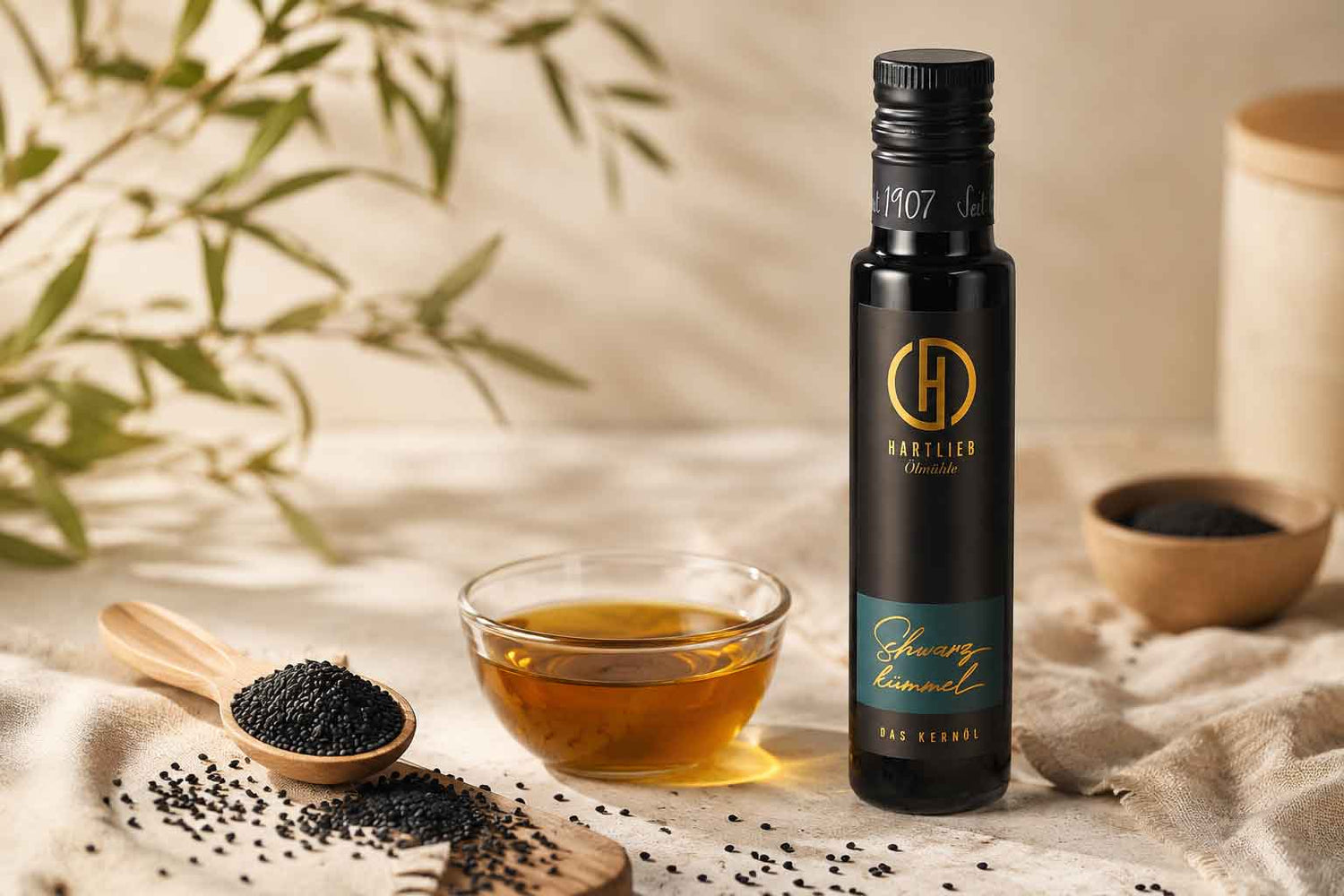 Schwarzkümmelöl neben einer Glasschale mit braun-gelben Öl