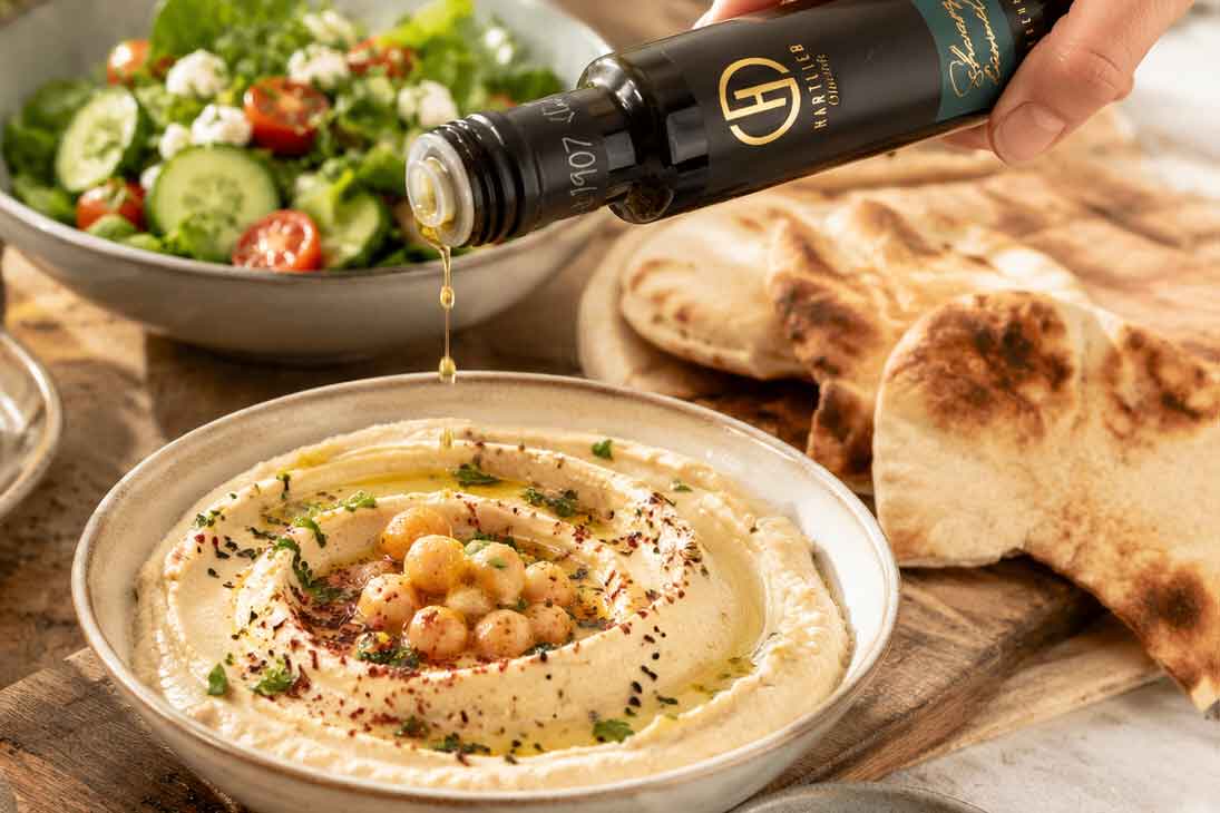 Schwarzkümmelöl von Hartlieb wird über Hummus getröpfelt