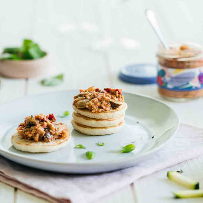 Teller mit Feinkosthäppchen und Glas mit Aufstrich.