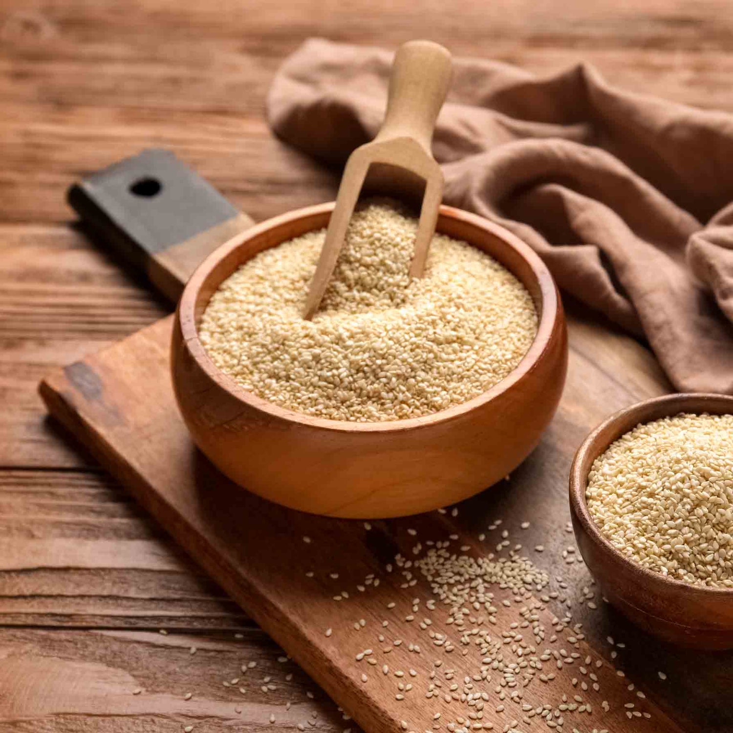 Sesamsamen in Holzschalen auf Holzbrett mit Schaufel.