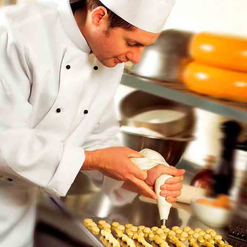 Koch dekoriert Gebäck in Küche.