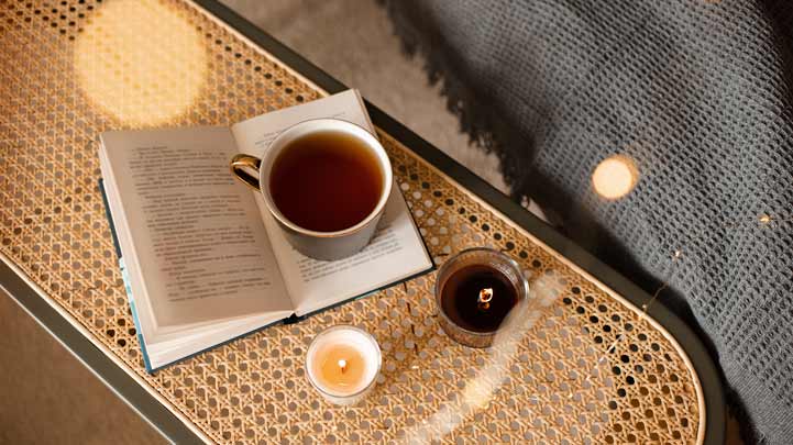 Buch, Tee, Kerze auf Tisch.
