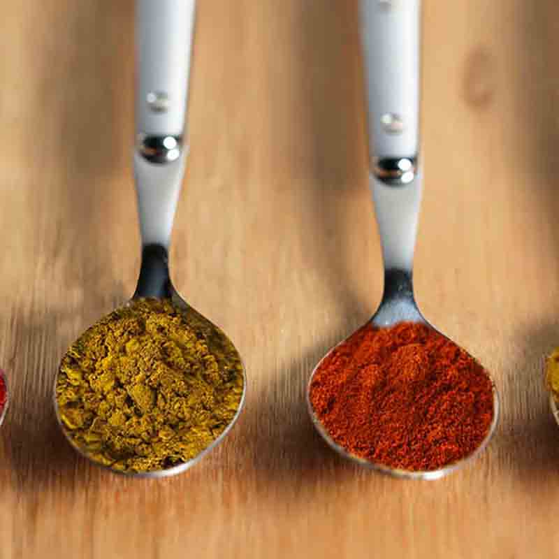 Löffel mit verschiedenen Gewürzen auf Holzuntergrund.