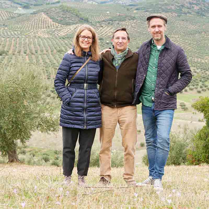 Bastian, Andrea und der Eigentümer von Soler Romero auf einem Olivenhain mit weitläufigen Olivenbäumen.