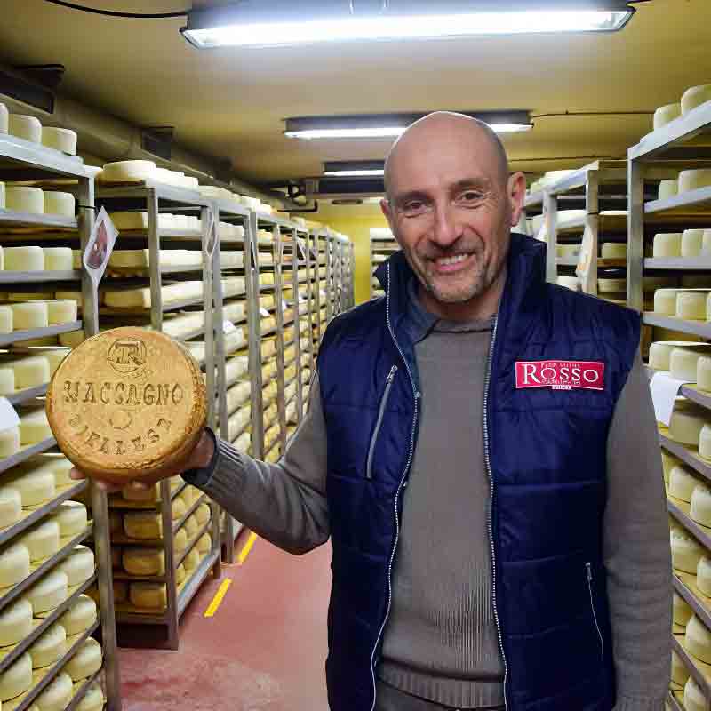 Mann in Käselager mit Käserad.