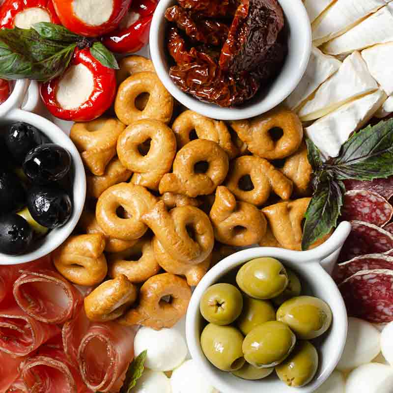 Antipasti-Platte mit Taralli, Oliven, Käse und getrockneten Tomaten.