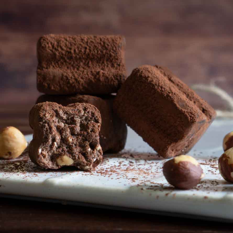 Schokoladentrüffel und Haselnüsse auf einem Tisch arrangiert.