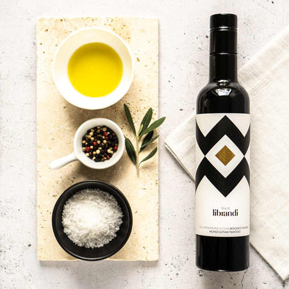 Olivenölflasche, Schalen mit Öl, Salz, Pfeffer, Olivenzweig.