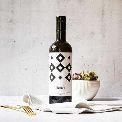 Olivenölflasche von Librandi auf Tisch mit Salatschüssel.