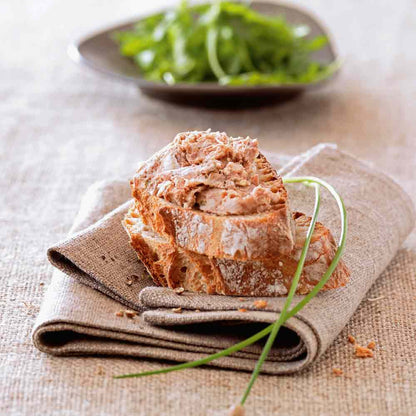 Brot mit Aufstrich auf Stoffserviette, Salat im Hintergrund.