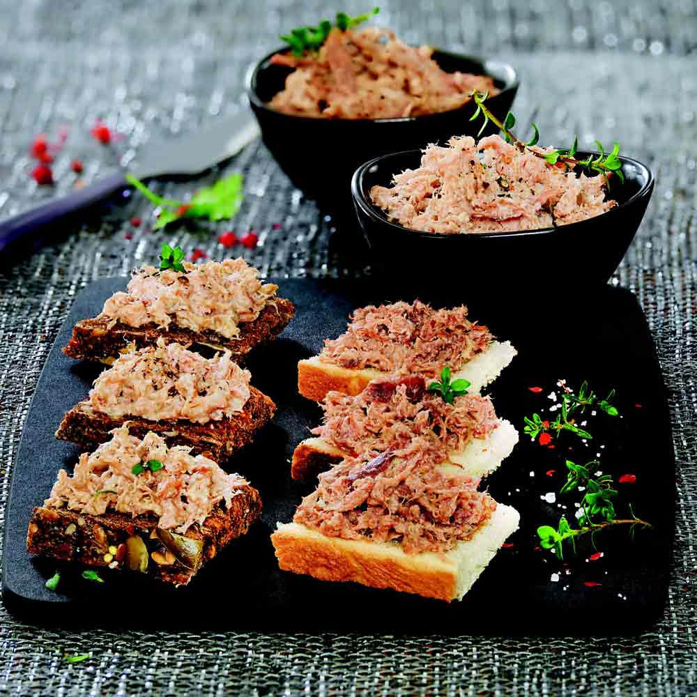 Terrinen und Rillettes auf Brot mit Kräuterdekoration.