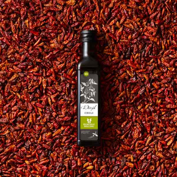 Flasche Olivenöl auf getrockneten Chilischoten.