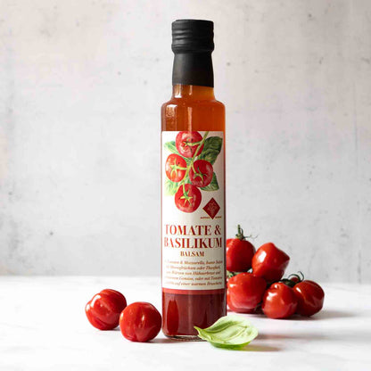 Tomate & Basilikum Balsam in Flasche, umgeben von frischen Tomaten und Basilikum. Perfekt für Salate und mediterrane Speisen.