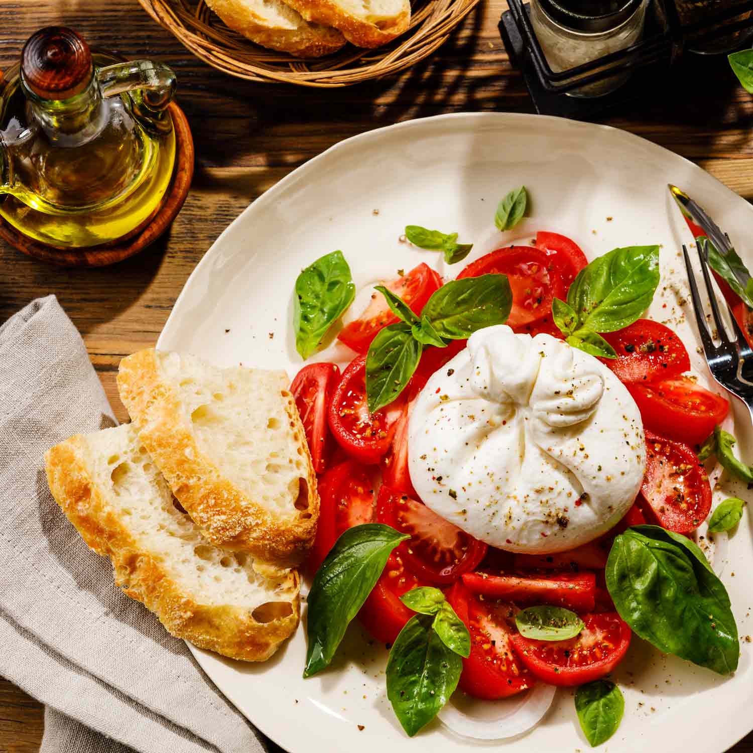 Tomatensalat mit Burrata, Basilikum, Brot und Olivenöl.