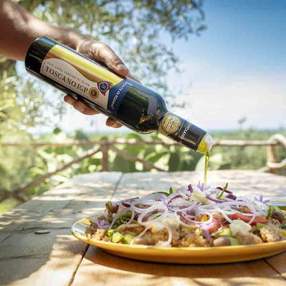 Olivenöl Toscano IGP über Salat im Freien gegossen.
