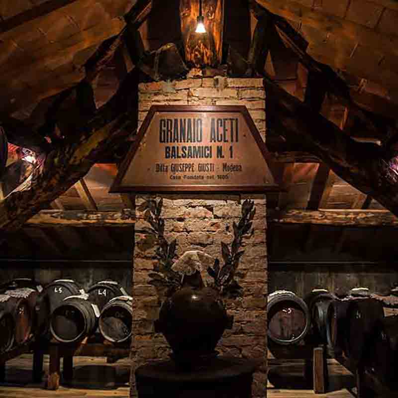 Traditionelle Balsamico-Essigfässer in rustikalem Lagerraum, Granai Aceti.