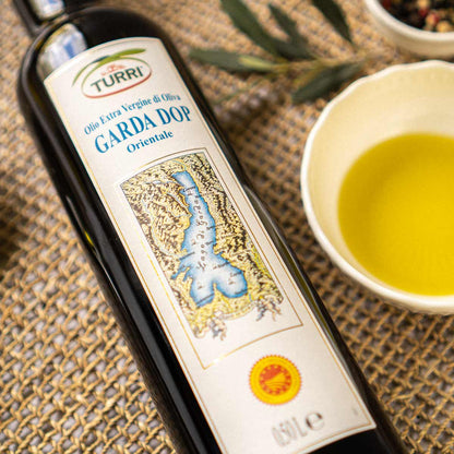 Turri Olivenölflasche mit Garda DOP Etikett auf Tisch.