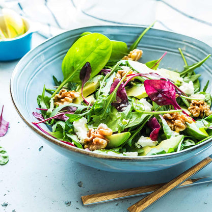 Salat mit Walnüssen, Blättern, Avocado und Käse in Schüssel.
