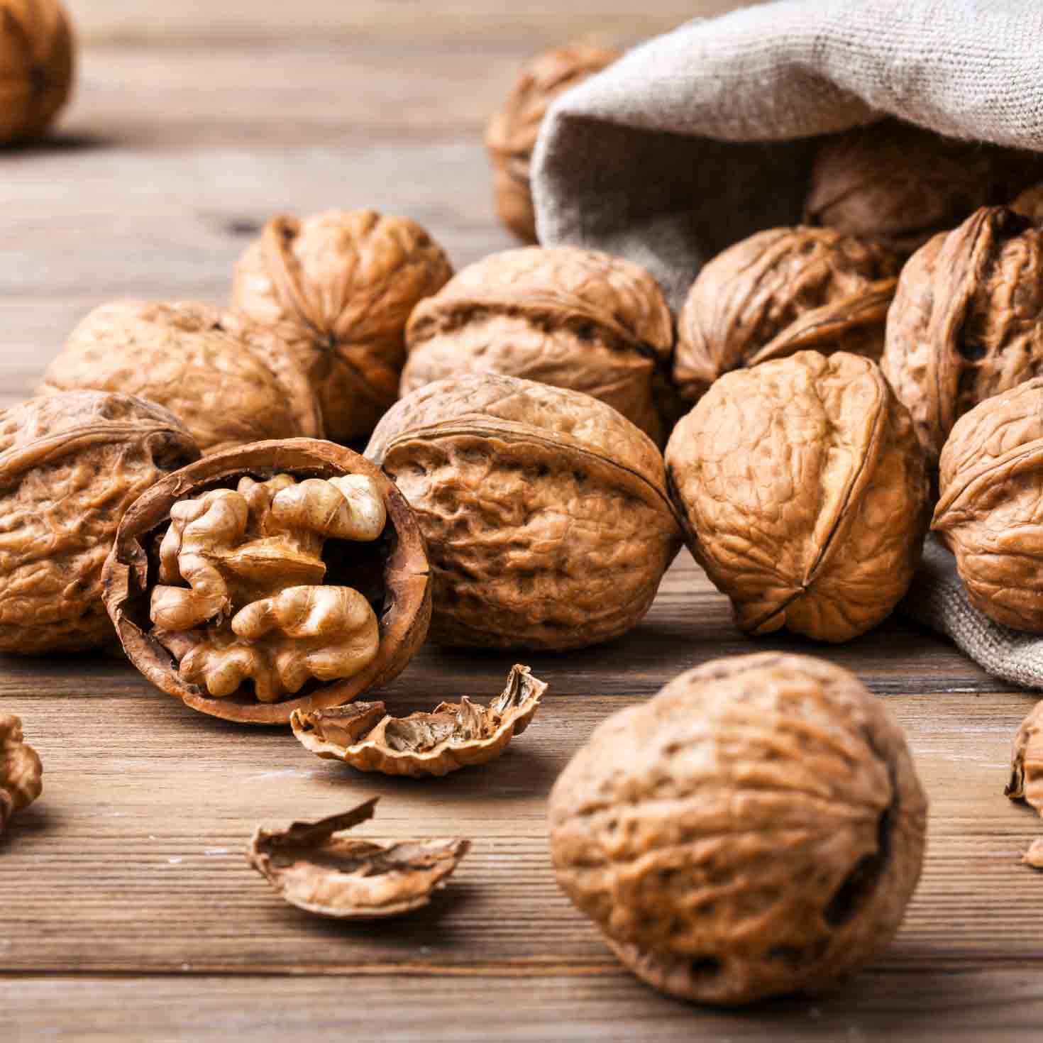 Walnüsse auf Holztisch, einige in geöffneter Schale.