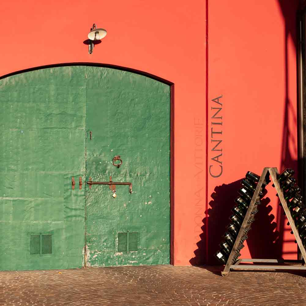 Grünes Tor, Cantina, Weinflaschen aufgestapelt, rotes Gebäude.