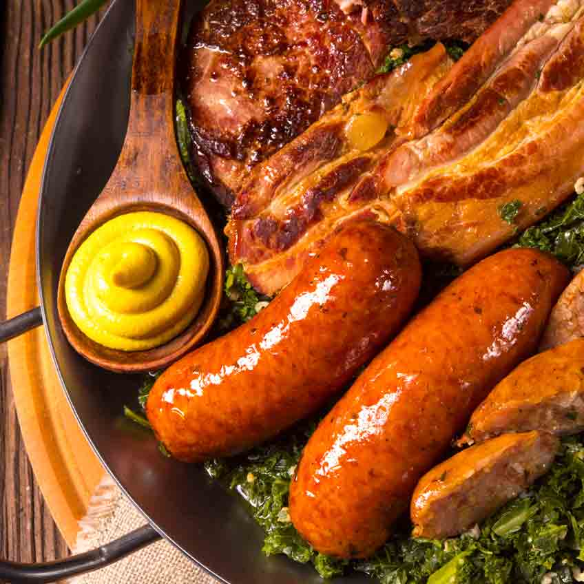 Wurstplatte mit Senf, Speck und Grünkohl auf Teller.