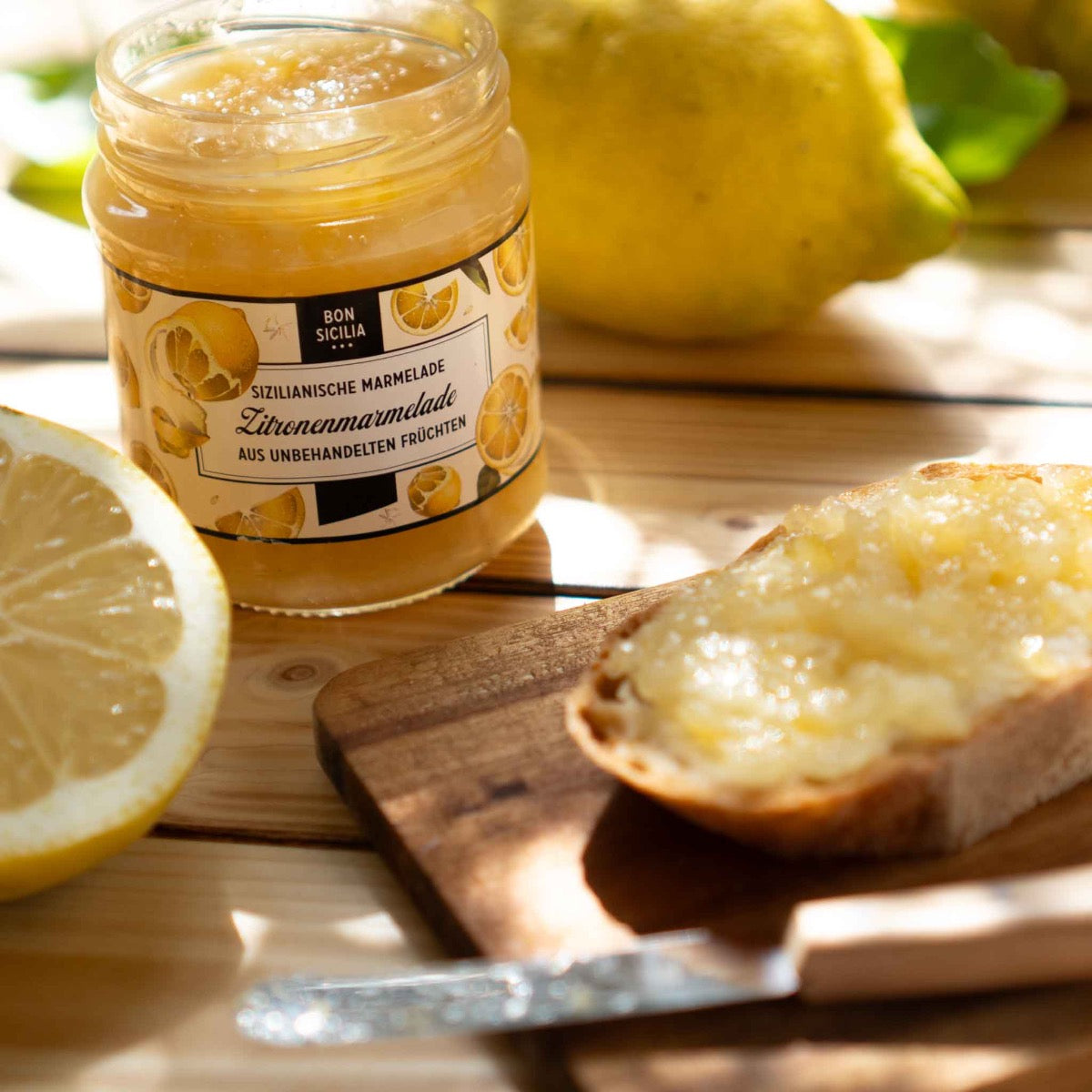 Zitronenmarmelade im Glas, Brot mit Marmelade, Zitrone daneben.