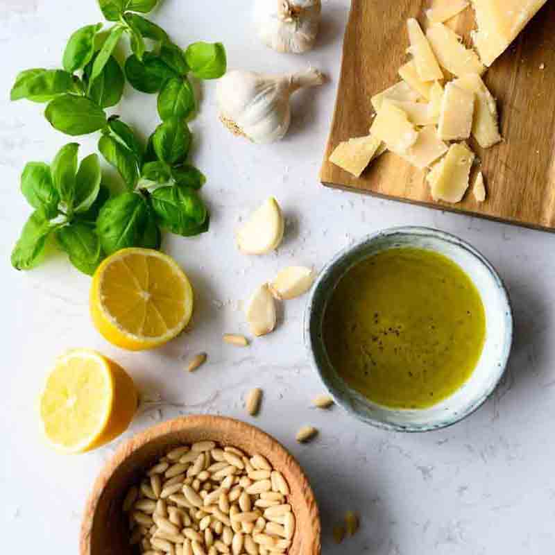 Basilikum, Knoblauch, Zitronen, Pinienkerne, Käse, Zitronenöl, Holzbrett.