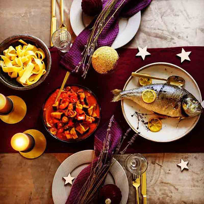 Feinkost-Tisch mit Fisch, Pasta, Gemüse, Kerzen und Dekoration.